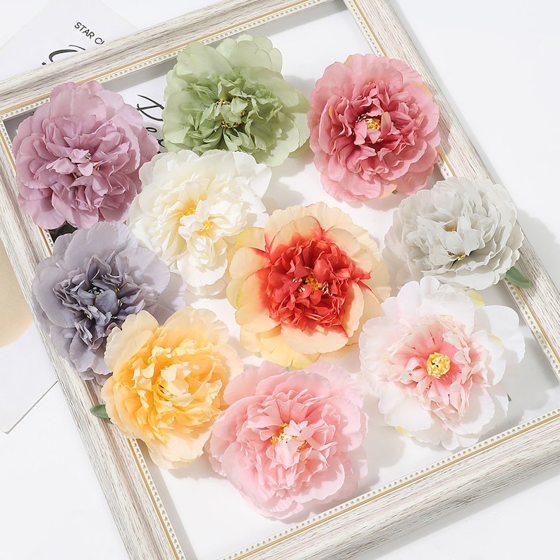 Puede incluir: Surtido de diez peon&iacute;as de seda artificial en varios colores, incluyendo rosa, blanco, melocot&oacute;n, rojo y verde. Las flores est&aacute;n dispuestas sobre un fondo blanco.