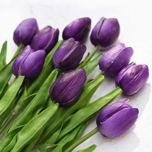 May include: A bouquet of purple artificial tulips with green stems and leaves.