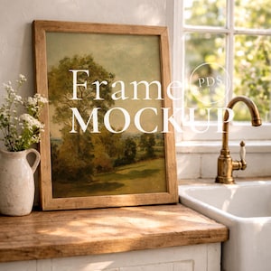 Könnte beinhalten: Ein gerahmtes Landschaftsgemälde mit dem Text "Frame MOCKUP" in einer Küchenszene. Das Kunstwerk zeigt einen Baum und ein Feld in Grün-, Gelb- und Brauntönen. Der Rahmen ist aus hellem Holz. Links steht eine weiße Vase mit Blumen.