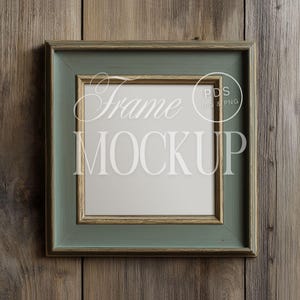 Peut inclure: Cadre photo carré avec une finition vert et or vieillie. Le cadre porte les mots "Frame Mockup" en écriture blanche et en lettres majuscules. Le cadre est posé sur un fond en bois.
