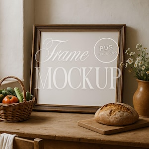 May include: A wooden framed mockup with the text "Frame Mockup" in a light color. A loaf of bread sits on a wooden cutting board. A basket of vegetables and a vase of flowers are also on the wooden table.