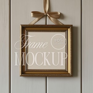 Puede incluir: Un marco de fotos dorado con un paspartú blanco y un fondo blanco colgado en una pared de madera blanca. El marco está atado con una cinta dorada. El texto "Frame Mockup" es visible en la imagen.