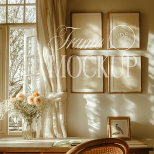 May include: A wooden desk with a book, a vase of flowers, and four empty picture frames with gold trim. The frames are hanging on a light beige wall. The desk is in front of a window with white curtains.