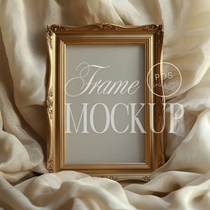 May include: A gold-colored ornate picture frame with a white background and the text "Frame Mockup" in white. The frame is sitting on a beige fabric background.