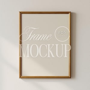 Op de afbeelding: Een rechthoekige gouden frame-mockup met de woorden "Frame MOCKUP" in een lichte kleur. Het frame hangt aan een neutraal gekleurde muur. De afbeelding bevat ook een kleine cirkel met de tekst "PDS JPG & PNG".