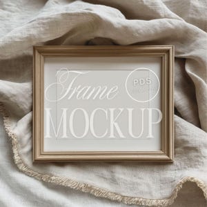 May include: A light brown wooden frame mockup on a beige linen fabric background. The frame has a white mat and the text "Frame Mockup" is printed in white on the mat.