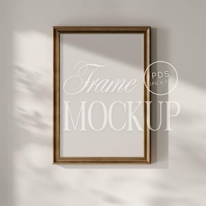 May include: A gold-colored picture frame mockup on a white wall with a shadow from a window. The frame is empty and ready for your design.