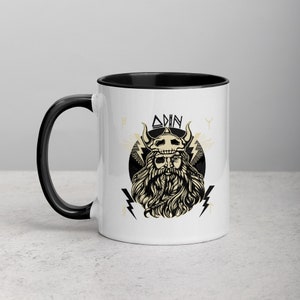 May include: White ceramic mug with a black rim and handle. The mug features a black and white illustration of Odin, a Norse god, with the text "ODIN" above him.