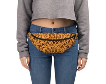 May include: A brown and black leopard print fanny pack with a black zipper. The fanny pack is worn around the waist of a person wearing blue jeans.