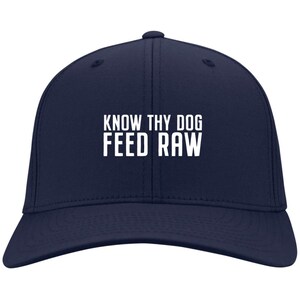 Puede incluir: Una gorra de béisbol azul marino con el texto "KNOW THY DOG FEED RAW" en blanco.