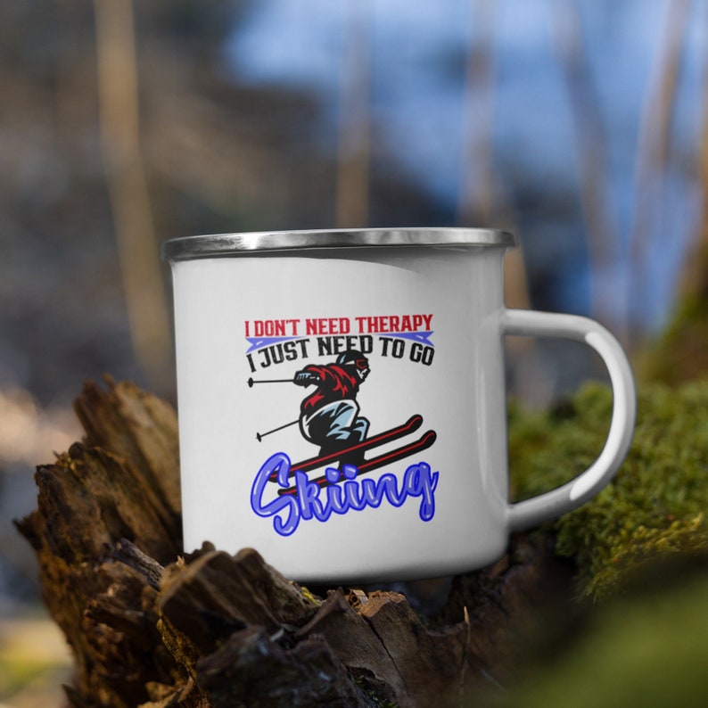 May include: White enamel mug with a blue and red graphic of a skier and the text "I don't need therapy I just need to go Skiing".