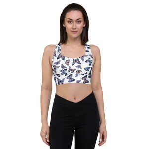 May include: A white sports bra with a butterfly print. The butterflies are in shades of blue and pink.