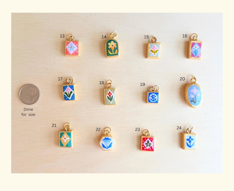 May include: A collection of twelve small gold-toned metal charms with colorful enamel floral and geometric designs, numbered 13 through 24. A US dime is included for scale, labeled as Dime for size, next to the charms arranged in three rows.