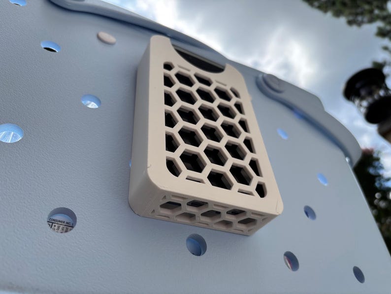 May include: A light blue tote bag with a white, rectangular, honeycomb-patterned attachment. The bag has several circular cutouts. The attachment is mounted on the side of the bag.