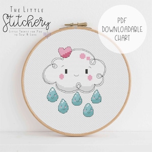Puede incluir: Un patrón de punto de cruz con una linda nube de dibujos animados con un corazón en la parte superior y gotas de lluvia con caras sonrientes. El patrón está en un aro de bordado de madera y el texto "PDF DOWNLOADABLE CHART" está en la esquina superior derecha.