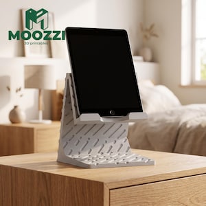 May include: A light gray 3D printed tablet stand with a textured pattern of diagonal slots and a flat base, holding a black tablet. The stand features the text MOOZZI 3D printables in green at the top left corner of the image frame.