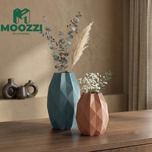 May include: Two geometric vases, one teal and one terracotta, hold dried flowers and greenery. The vases are on a wooden surface. The logo "MOOZZI 3D printables" is in the upper left corner.