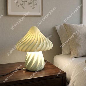 May include: A whimsical mushroom-shaped table lamp with a cream-colored, swirled lampshade and base. The lamp sits on a dark wooden nightstand, casting a warm glow. A framed mushroom illustration hangs on the wall.