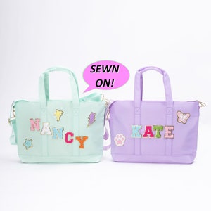 May include: Two personalized tote bags, one light green with the name "NANCY" in colorful letters and the other lavender with the name "KATE" in colorful letters. Both bags have various colorful patches sewn on.