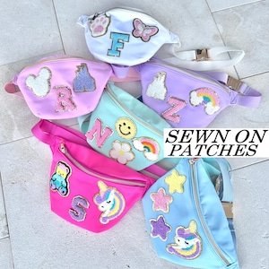 May include: Six colorful fanny packs with various embroidered patches. The patches include letters, animals, stars, rainbows, and flowers. The text on the image reads "SEWN ON PATCHES".