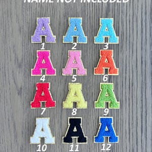 K&ouml;nnte beinhalten: Eine Sammlung von zw&ouml;lf gestickten Buchstaben-Patches in verschiedenen Farben, darunter Lila, Blau, Rosa, Orange, Rot, Gelb, Gr&uuml;n, Wei&szlig;, Schwarz und Blau. Jeder Buchstabe ist goldfarben umrandet und von 1 bis 12 nummeriert.