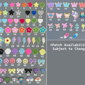 May include: A collection of embroidered patches in various shapes and colors, including stars, hearts, flowers, crowns, and butterflies. The patches are numbered and arranged on a gray background. Text at the bottom reads, "Patch Availability Subject to Change."