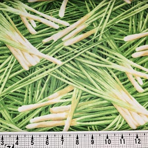 May include: Fabric with a repeating pattern of green blades of grass and off-white, elongated shapes. The design has a natural, botanical theme, with a mix of light and dark green hues. The fabric is likely cotton or a similar material.