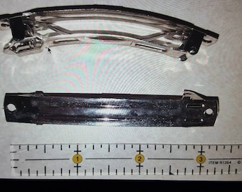 May include: Two silver metal hair clips, one is curved and the other is straight. The clips are shown next to a ruler with markings in inches.
