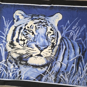 May include: A blue and white tiger illustration on a black background. The tiger is depicted in a realistic style, with detailed fur and facial features. The image includes tall grass in the foreground.