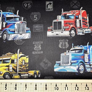 May include: A black fabric with a repeating pattern of semi-trucks. The trucks are blue, red, and yellow. The trucks have different route numbers on the sides, including "Historic Route 66", "Missouri US 66", and "California US 66".
