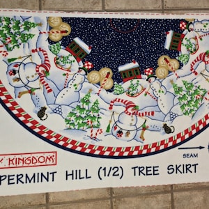 May include: A white Peppermint Hill (1/2) tree skirt with a festive winter scene. The design features snowmen, Christmas trees, candy canes, and a navy blue sky with falling snow. The skirt has a red and white checkered border.