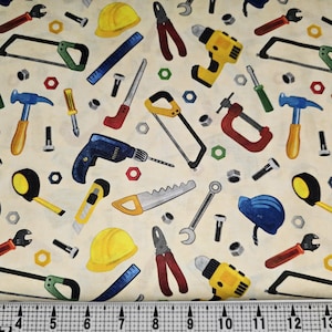 May include: Fabric with a repeating pattern of construction tools. The design includes hammers, saws, drills, wrenches, and hard hats in various colors, such as yellow, blue, red, and green, on a cream background.