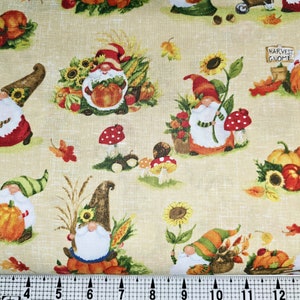 May include: A beige fabric with a repeating pattern of gnomes, pumpkins, sunflowers, and mushrooms. The gnomes are wearing red, green, and blue hats and have white beards. The pumpkins are orange and yellow. The sunflowers are yellow with brown centers. The mushrooms are red with white spots. The fabric has the text "Harvest Gnome" on it.