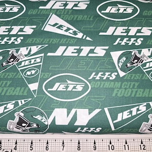 May include: Green fabric with a repeating pattern of the New York Jets logo, the words "Jets" and "J-E-T-S", and the words "Gotham City Football".