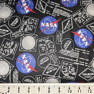 May include: Black fabric with a repeating pattern of NASA logos, moons, and text that says "Exploring the Universe" and "Inspiring the World through Discovery".
