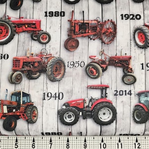May include: Fabric with a pattern of red tractors from different eras, including models from 1920, 1930, 1940, 1950, 1960, 1970, 1980, 2014, and 2020, set against a gray and white wood-grain background.