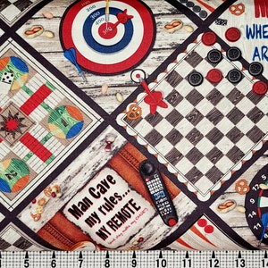 May include: A colorful fabric with a woodgrain background featuring various game boards, including a dartboard, checkers, a target, and a game of Parcheesi. The fabric also includes a remote control, pretzels, and the text "Man Cave my rules... MY REMOTE".