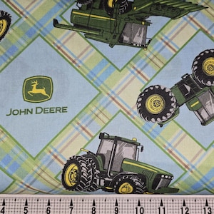May include: Blue and green fabric with a plaid pattern and repeated images of John Deere tractors. The fabric features the John Deere logo with a green deer and the words "John Deere".
