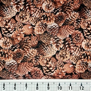 May include: A brown and beige fabric with a repeating pattern of pine cones. The fabric is perfect for crafting projects, quilting, and home decor.