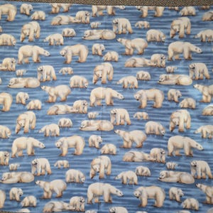 Może przedstawiać: Niebieski koc z powtarzającym się wzorem niedźwiedzi polarnych i ich młodych. Niedźwiedzie przedstawione są w różnych pozach, stojące, chodzące i leżące, na tle niebieskich linii przypominających wodę.