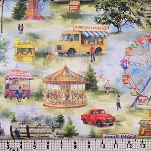 May include: A fabric print with a watercolour illustration of a state fair. The scene includes a Ferris wheel, carousel, food stalls, a red truck, and a vintage car. The words "STATE FAIR" are visible.
