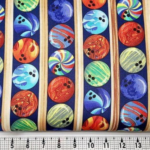 以下が含まれることがあります： さまざまな色とデザインのボウリングボールが繰り返されるパターンが施された青い生地。ボウリングボールは、茶色のストライプで区切られた縦の列に配置されています。