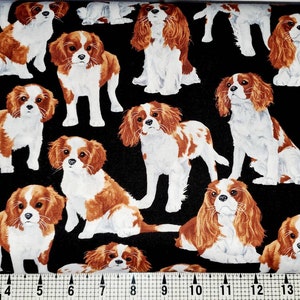 Könnte beinhalten: Ein schwarzer Stoff mit einem sich wiederholenden Muster aus braunen und weißen Cavalier King Charles Spaniel Hunden. Die Hunde sind in verschiedenen Posen, einige sitzen, einige stehen und einige liegen.