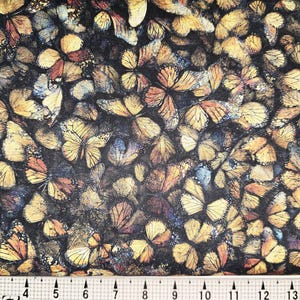 Peut inclure: Tissu avec un motif dense de papillons dans des tons de jaune, orange et marron sur un fond sombre. Les papillons varient en taille et sont disposés pour créer un effet texturé et superposé. Mesure en centimètres.