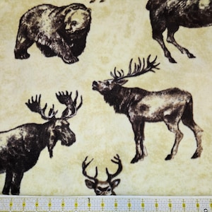 Może przedstawiać: Beżowa tkanina z powtarzającym się wzorem leśnych zwierząt w odcieniach brązu, w tym niedźwiedzi, łosi, jeleni i wapiti. Zwierzęta są szczegółowo zilustrowane, tworząc rustykalny, outdoorowy motyw.