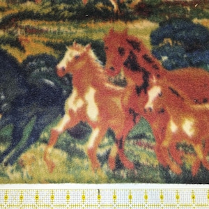 Może przedstawiać: Tkanina z powtarzającym się wzorem koni biegnących po trawiastym polu. Konie są w odcieniach brązu, czerni i bieli. Tło przedstawia zielone i niebieskie liście.