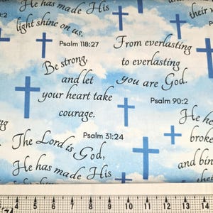 May include: A patterned fabric with a sky-blue background, white clouds, and blue crosses. The fabric is inscribed with religious text, including phrases from Psalms, such as "He heals the brokenhearted."