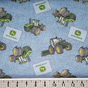 Pode incluir: Tecido azul com um padrão repetido de tratores e logotipos John Deere verdes. O tecido é texturizado para parecer denim.