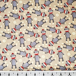 Może przedstawiać: Beżowy materiał z powtarzającym się wzorem szarych małp w skarpetkach z czerwonymi czapkami. Małpy stoją na nogach z wyciągniętymi ramionami. Na materiale rozrzucone są małe brązowe kółka.