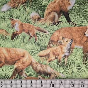 Może przedstawiać: Druk na tkaninie z powtarzającym się wzorem czerwonych lisów na zielonym trawiastym polu. Lisy są w różnych pozach, w tym chodzą, biegną i siedzą. Tkanina jest idealna do projektów rzemieślniczych, takich jak kołdry, poduszki i torby.